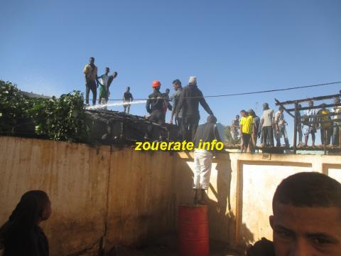 صورة من المنزل الرابع، وفي الصورة أيضا فريق الإطفاء يحاول إخماد الحريق في المنزلين المجاورين للمنزل الأول